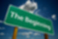 Green sign with "The Beginning" text against a blue sky with clouds. Bright and optimistic mood.