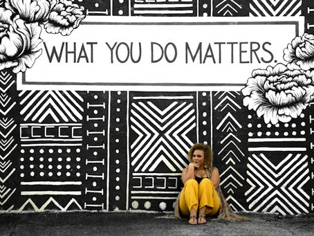 Sign that says what you do matters in black and white with a woman sitting