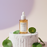 Centella serum bottle on a white platform with surrounding greenery Fresh Aura BDA