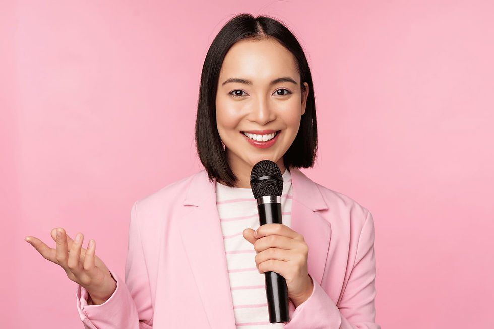 femme-d-affaires-asiatique-prononcant-un-discours-tenant-un-microphone-et-souriant-debout-en-costume-sur-fond-rose
