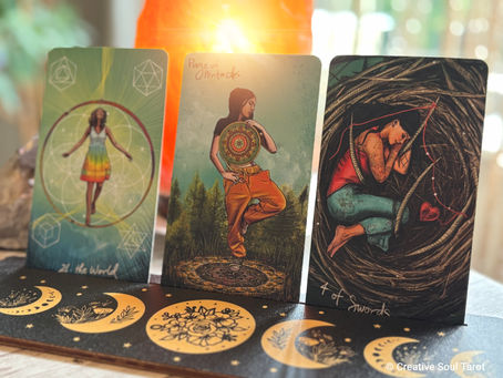 Three tarot cards on a decorated mat with moon phases. Cards depict The World, Page of Pentacles, and 4 of Swords in vivid art.