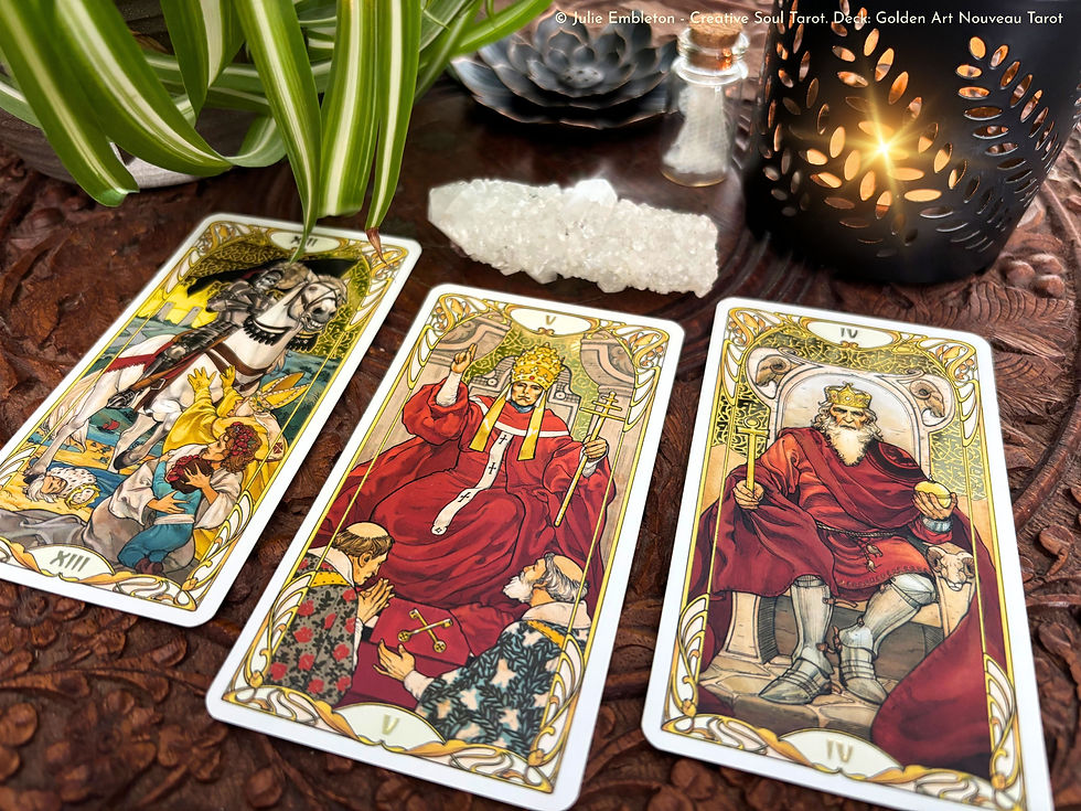 Three tarot cards—Chariot, Hierophant, Emperor—on carved wood with crystal, plant leaves, and a glowing candle.
