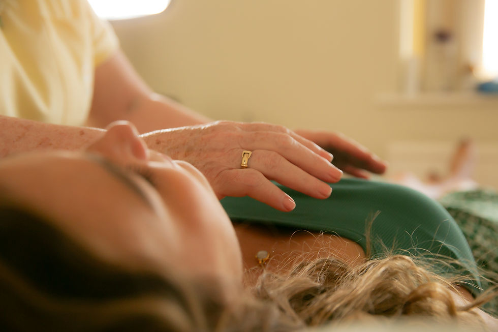 Close-up of a hand gently resting on someone lying down, with blurred background. The hand wears a gold ring. Warm, relaxed mood.