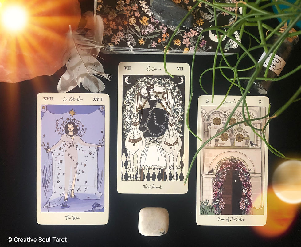 Tarot cards on a black velvet cloth with feathers, crystals and a candle.
