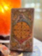 The Wheel of Fortune Tarot card with mystical symbols. Vibrant colors with lion, bull, and sphinx motifs. Warm orange glow in the background.