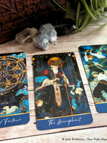 Three tarot cards on a wooden table with crystals and a plant: Wheel of Fortune, The Hierophant, and Five Of Wands.