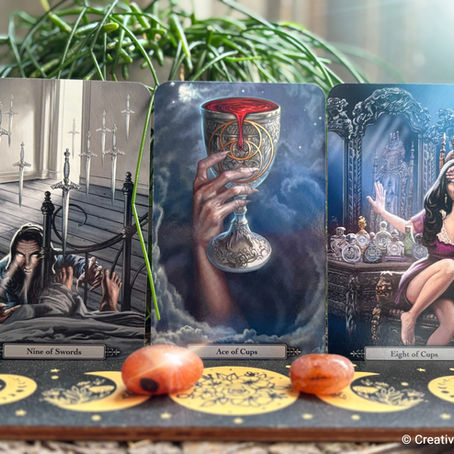 Three tarot cards on a decorated surface: Nine of Swords, Ace of Cups, and Eight of Cups. Background has plants and soft lighting.