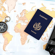 a compass lying on the left side of a world map with a passport, camera and cell phone nex