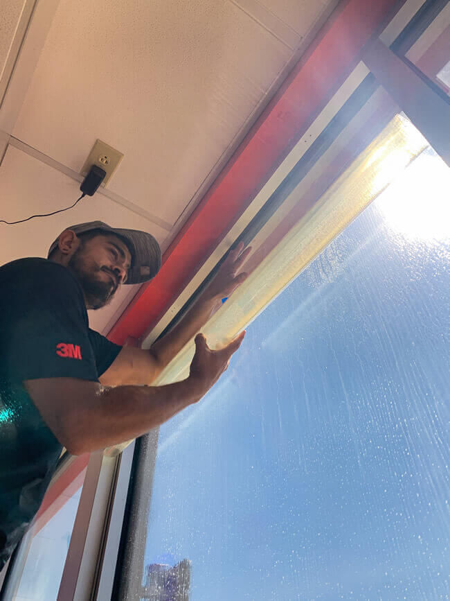 Technician applying security window film to commercial glass door for added break-in protection
