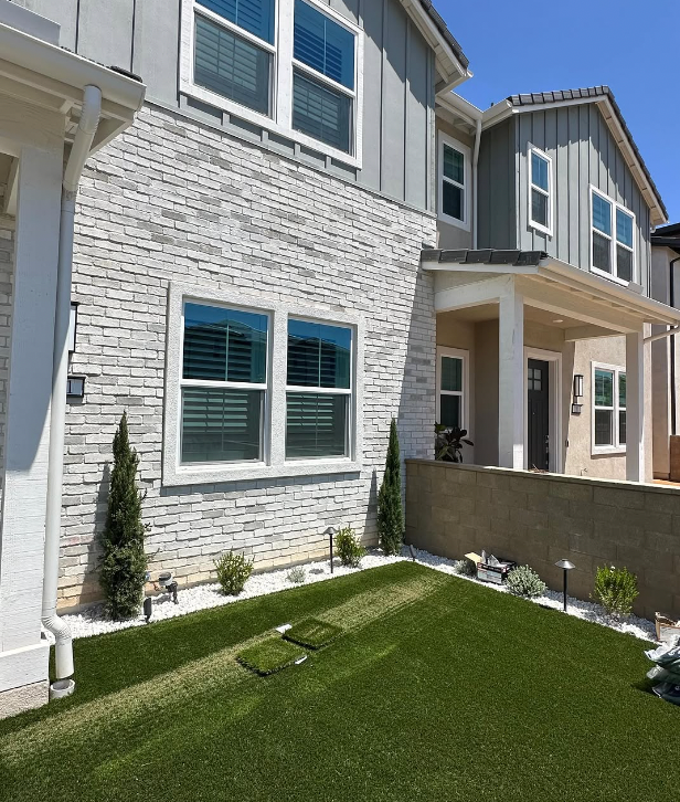 Home exterior with low-e windows positioned above artificial turf showing a common turf burn risk area