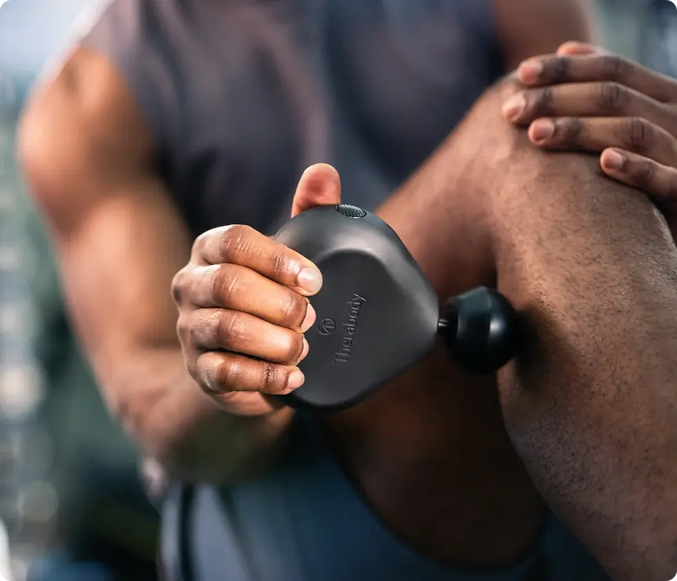 “Theragun Mini massage gun in black, a compact muscle recovery tool popular with men.”