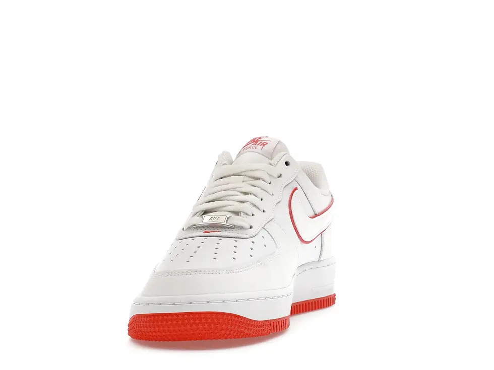 White Nike Air Force 1 sneaker with red swoosh, "Nike Air" tongue, red sole.
