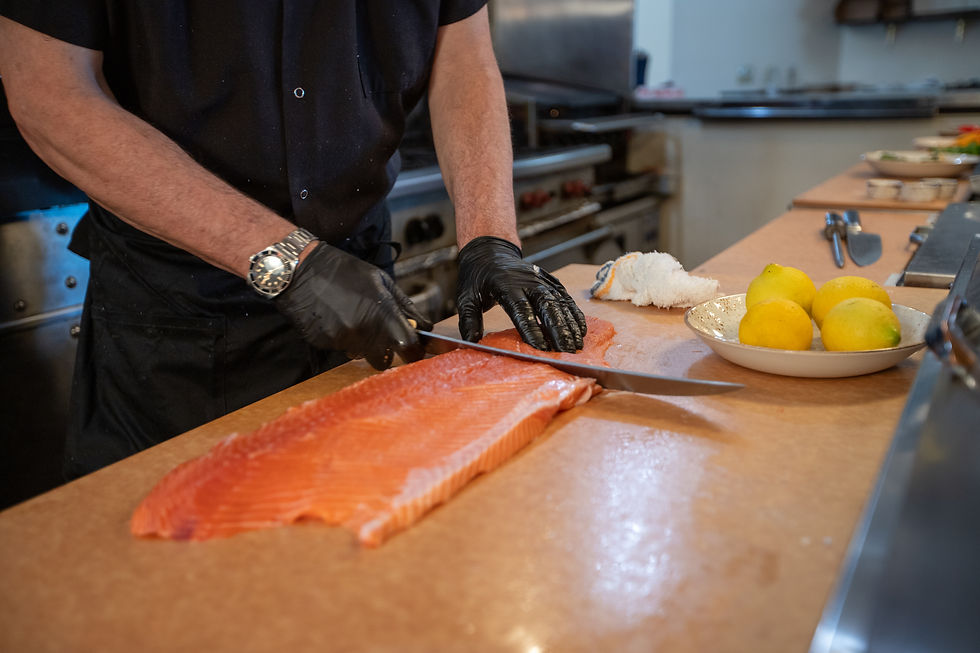 In a restaurant kitchen, a chef fillets a salmon on a Richlite surface, showcasing its versatility as a cutting board.