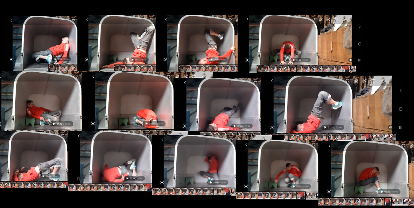 Sequence of Eddie Ladd doing movements inside an animal container. she is wearing red and grey clothes.