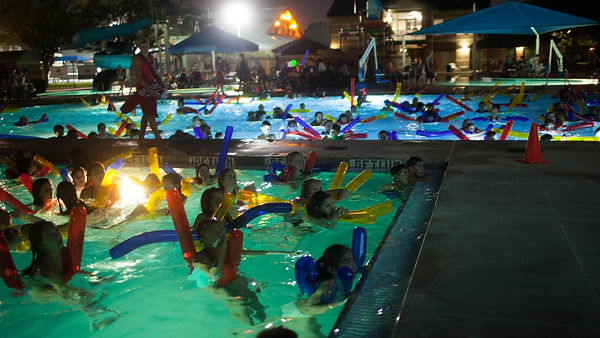 Families watching a movie from the pool at Dive-In Movie Night, Bellaire Town Square Family Aquatic Center