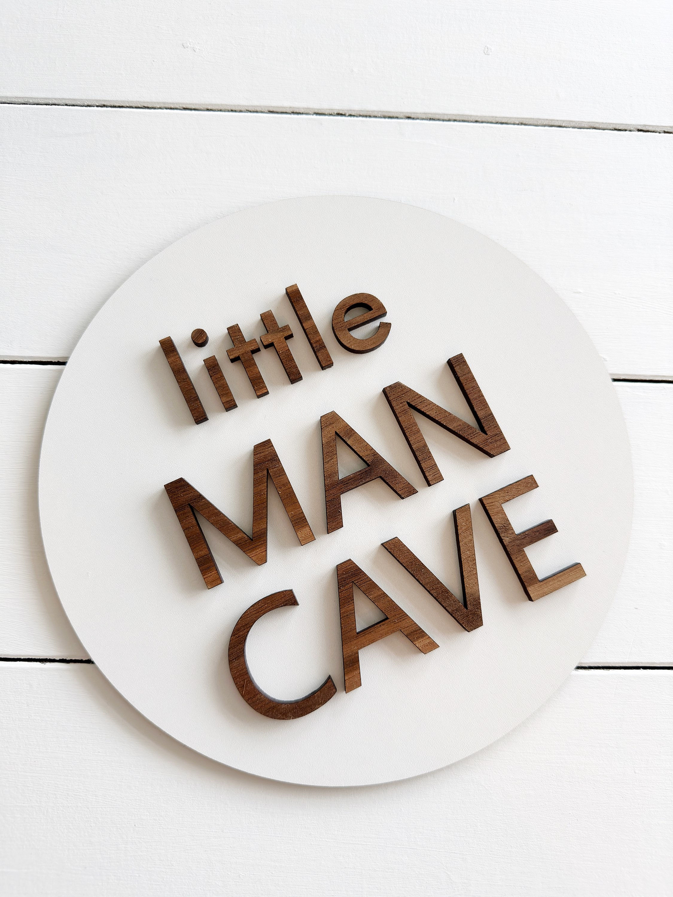 white circle sign with walnut wood lettering Little Man Cave