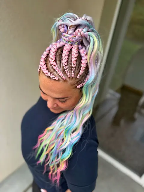 Žena s barevnými copánky, modré tričko, složitý účes a vlnité vlasy.