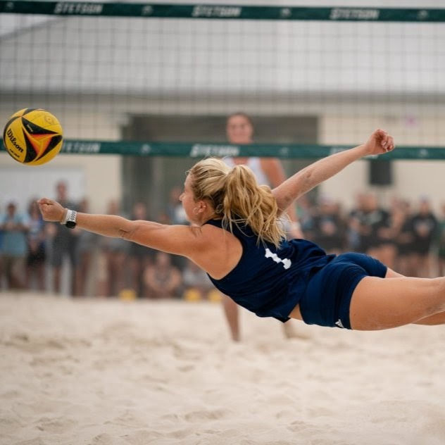 Photo of Alivia Orvieto diving for a volleyball in a beach volleyball match, previously training for