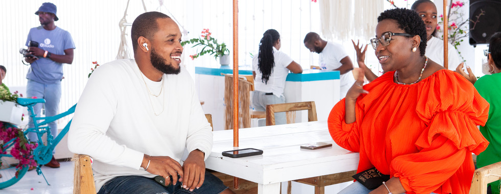 shoppers relax and chat at table under tent at artisan market in kingston jamaica