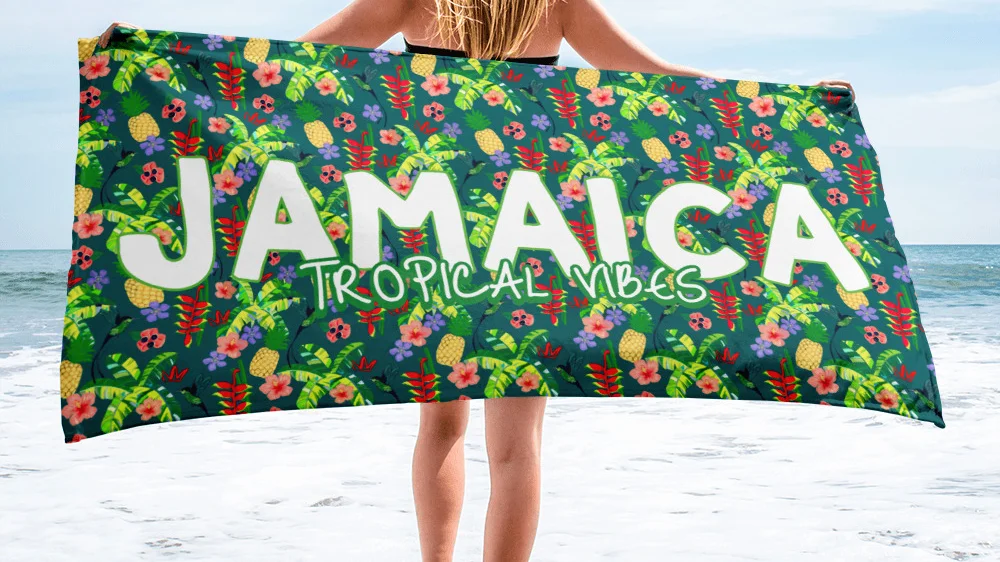 floral beach towel with Jamaica tropical text held spread out by woman on beach