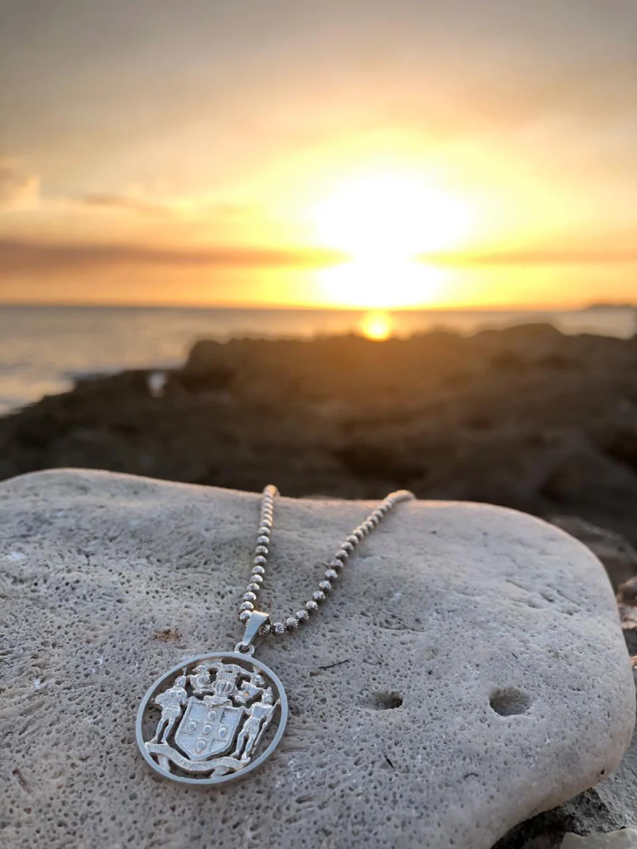 Jamaica Coat of Arms Pendant on rock with sunset in the background