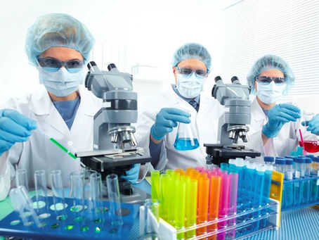 Three lab technicians working together in a brightly lit laboratory setting.