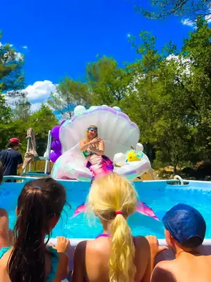 Freya la Sirène en animation piscine, assise sur une coquille géante et divertissant les enfants 