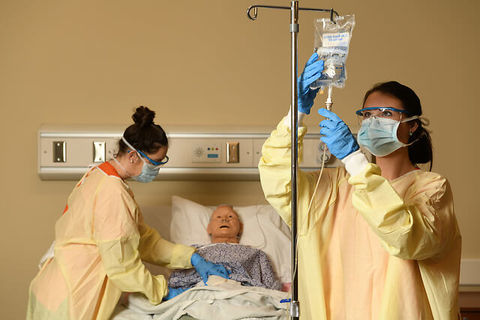 Two nurses adjusting an IV bag above a patient Simulation in a hospital room.