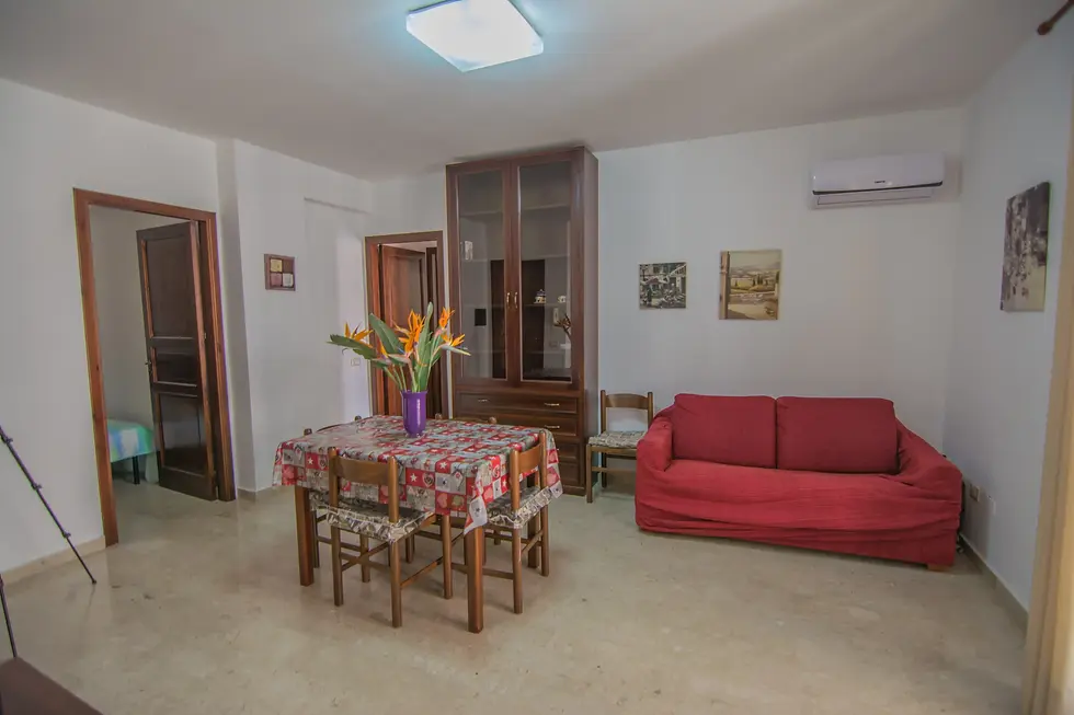 ampia zona relax con televisione, divano e tavolo per mangiare, con una luminosa finestra 