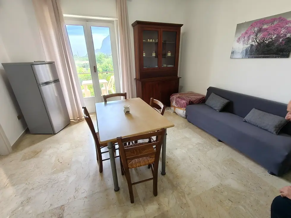 ampia sala da pranzo, con divano, tavolo e sedie e tv. finestra luminosa con panorama naturale ed urbano