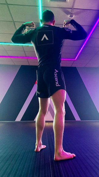"Instructor at Ascend Jiu Jitsu demonstrating techniques while wearing the custom black No-Gi kit by Raine Clothing. The kit includes a black rashguard and shorts, designed for optimal performance and comfort.