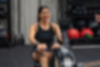 A close-up of a Latina woman in her 40s exercising on a rowing machine, focused and determined.