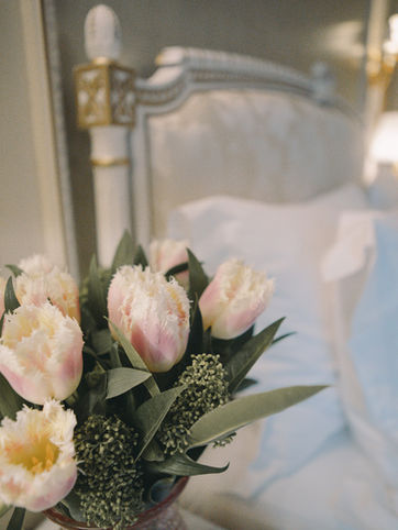 Bett und Blumenstrauß in einer Suite im Le Meurice Hotel in Paris