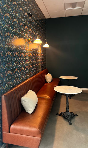 Cozy seating area with a long brown bench and small tables. Etc Hospitality