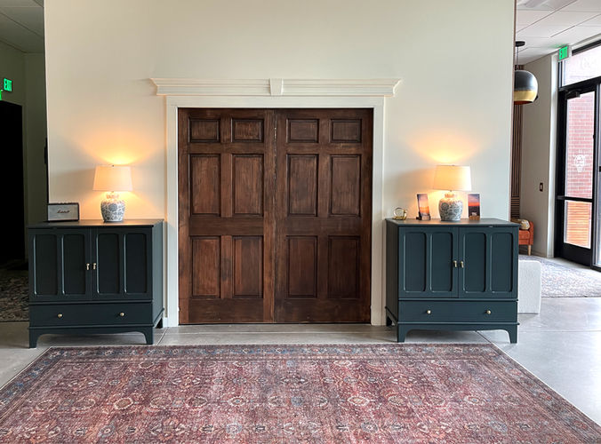 Wooden double doors flanked by cabinets and lamps, and a red rug. Setting: Hospitality.