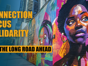 A vibrant mural of two Black women painted on a city wall in vivid colors—purple, orange, turquoise, and gold—set against a backdrop of tall urban buildings. The women’s expressions are strong and determined, symbolizing resilience and pride. Overlaid on the left side of the image in bold yellow and black text are the words: “CONNECTION. FOCUS. SOLIDARITY. FOR THE LONG ROAD AHEAD.”