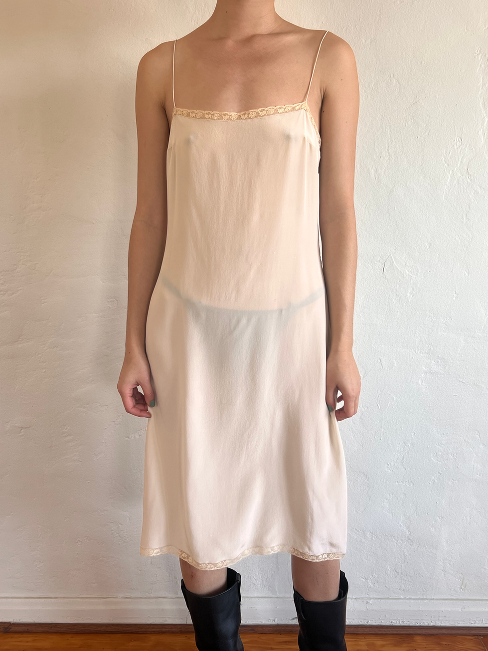Woman wearing a sheer white slip dress with lace trim.