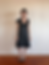 Woman wearing a black dress and black heels in front of a white wall
