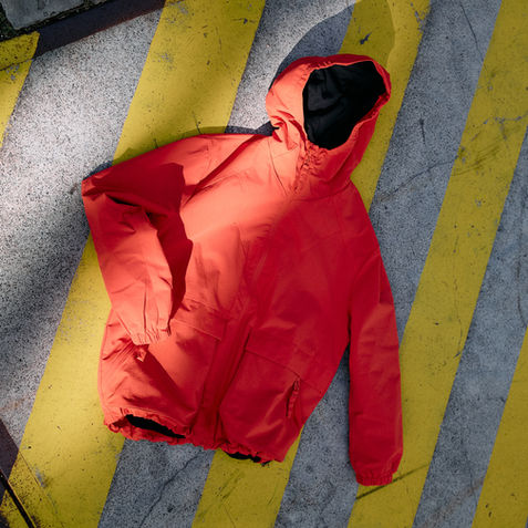 Rote Kapuzenjacke der SS26 Kollektion auf Bodenmarkierung
