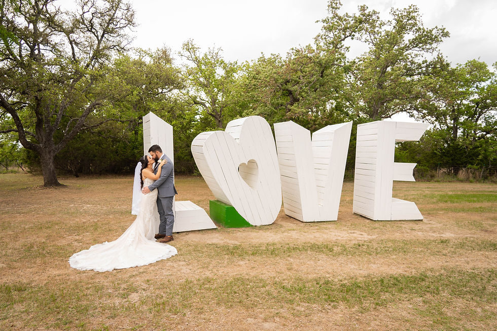 Bride and groom kiss in front of large LOVE sign