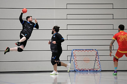 Groupe d’adultes jouant au tchoukball lors d’un entraînement, lançant la balle vers le cadre.