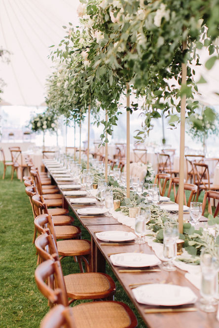 Image captures the breathtaking beauty of a meticulously planned wedding orchestrated by A Stephens Soirée. The focal point is the head dinner table nestled under a graceful canopy tent, evoking an ambiance of elegance and intimacy. The table is adorned with a magnificent arrangement of white roses, their delicate petals exuding timeless beauty and romance. Intricate floral arrangements gracefully weave through the crystal glassware, adding a touch of enchantment to the table setting. This captivating image showcases A Stephens Soirée's commitment to curating visually stunning and inclusive weddings, where every element, from the meticulously arranged flowers to the artful design, contributes to an unforgettable celebration of love and refinement.