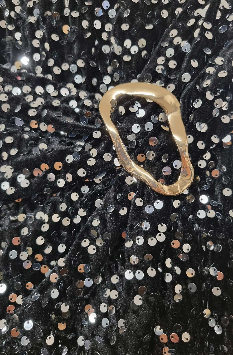 Close-up of black sequin fabrick and gold buckle detail.