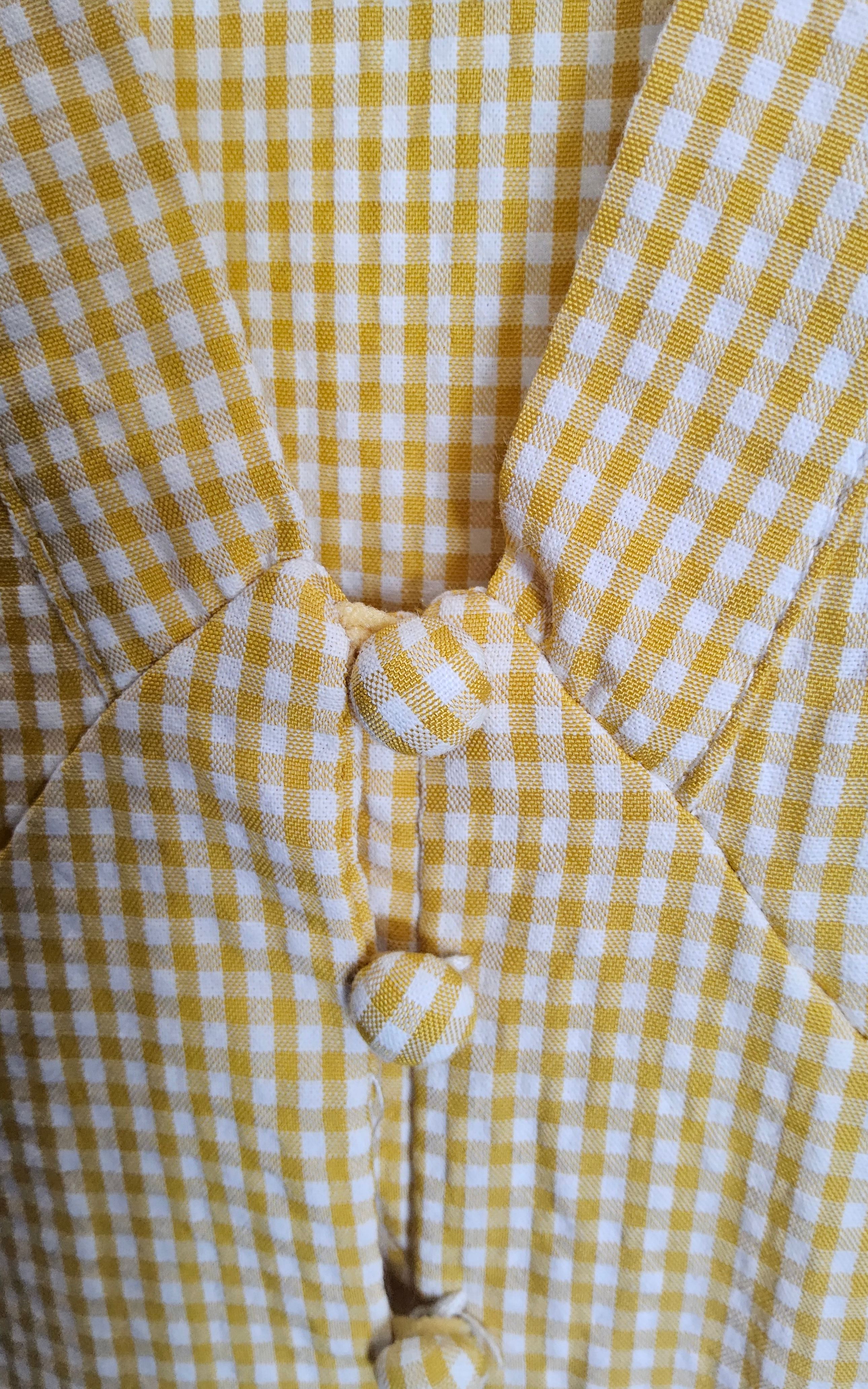 Close-up detail of yellow gingham fabric and covered button front