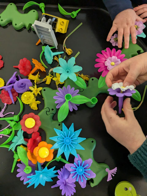 Childrens hands playing with plastic flower toys that fit together