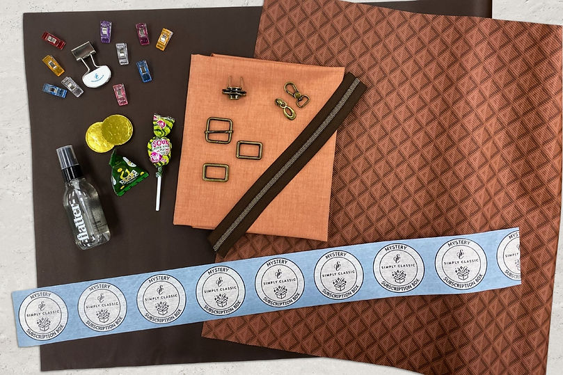 Sample contents of a bag making subscription box with faux leather, lining, hardware, candy, notions, and more