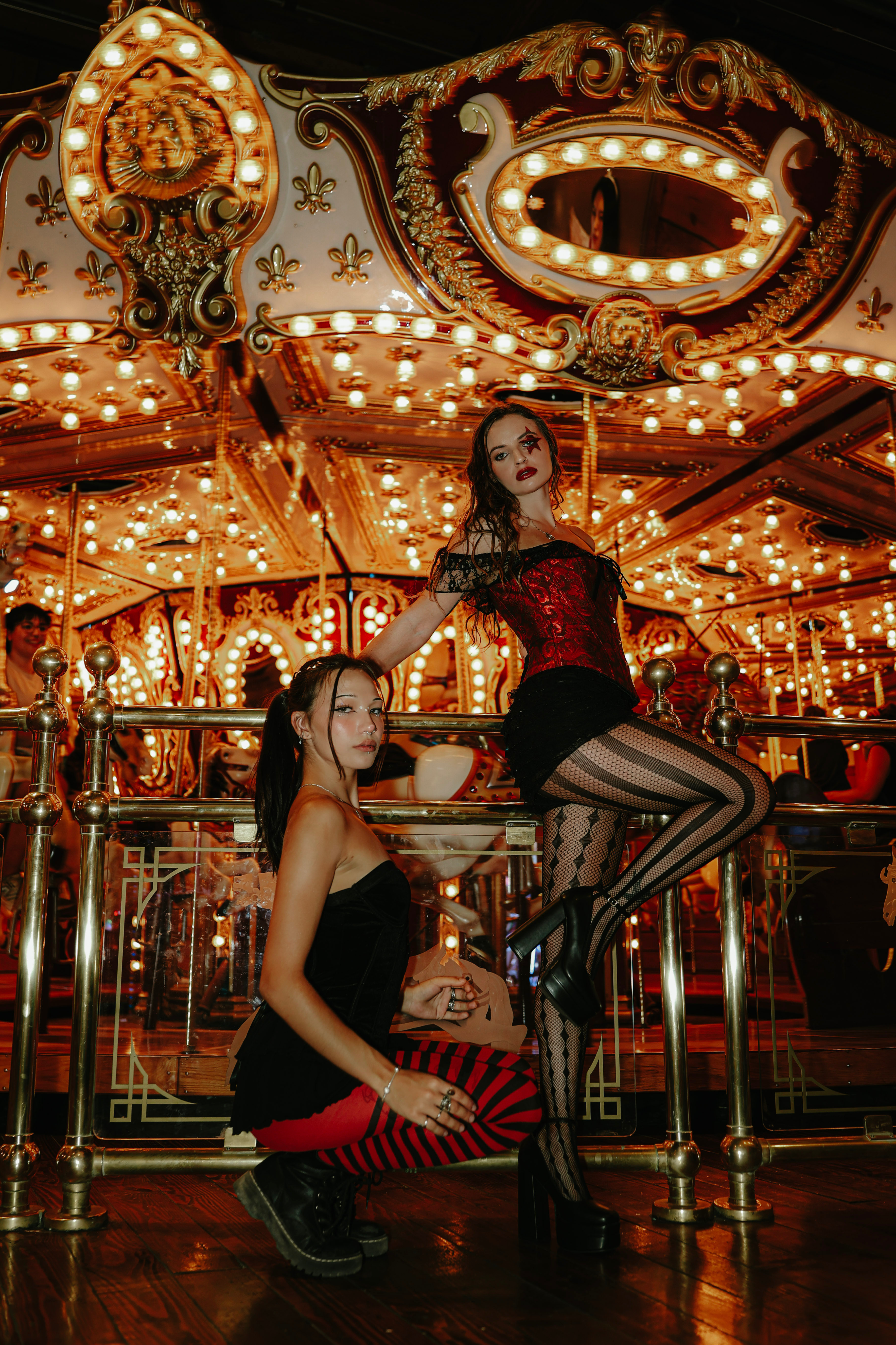 Two women posing in front of an illuminated carousel