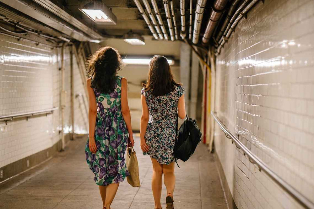 two women carrying bags while walking in tunnel