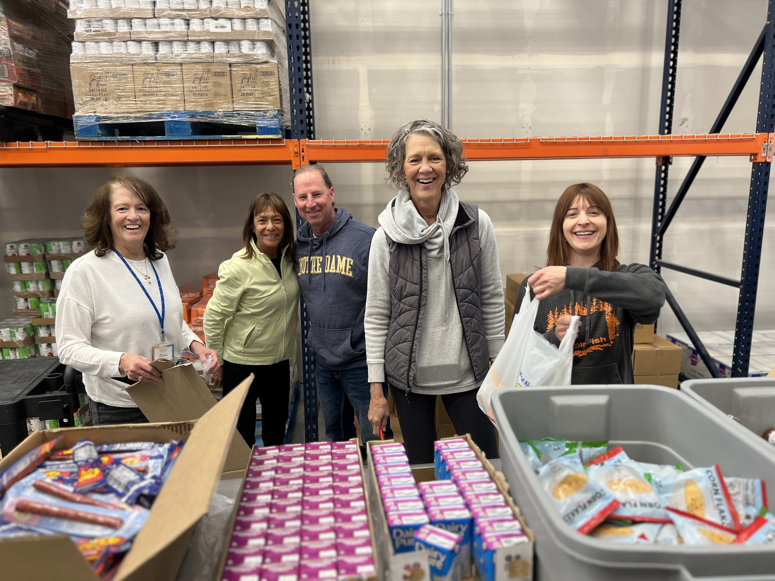 SECOR volunteers beside food supplies in the warehouse.