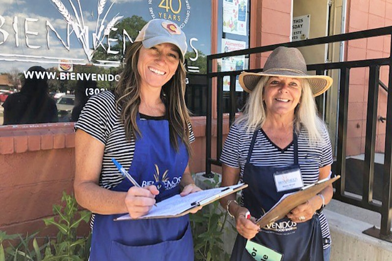 Two Bienvenidos volunteers with clipboards outside the food bank.